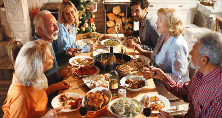 A group of senior men and women sitting at a table eating Thanksgiving food