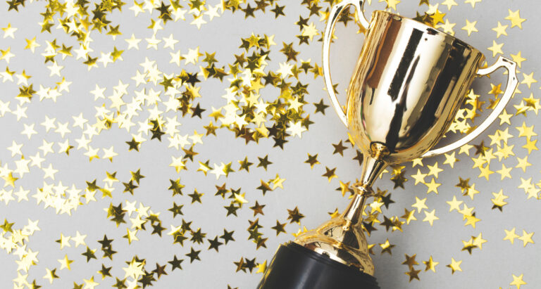 A gold trophy lying on a table with small gold stars scattered around it